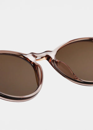 Sunglasses with rose gold frame and brown lenses on a light gray background