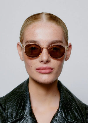 Woman wearing sunglasses and a black leather jacket against a plain background