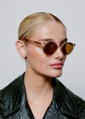 Woman wearing round sunglasses with a plain background