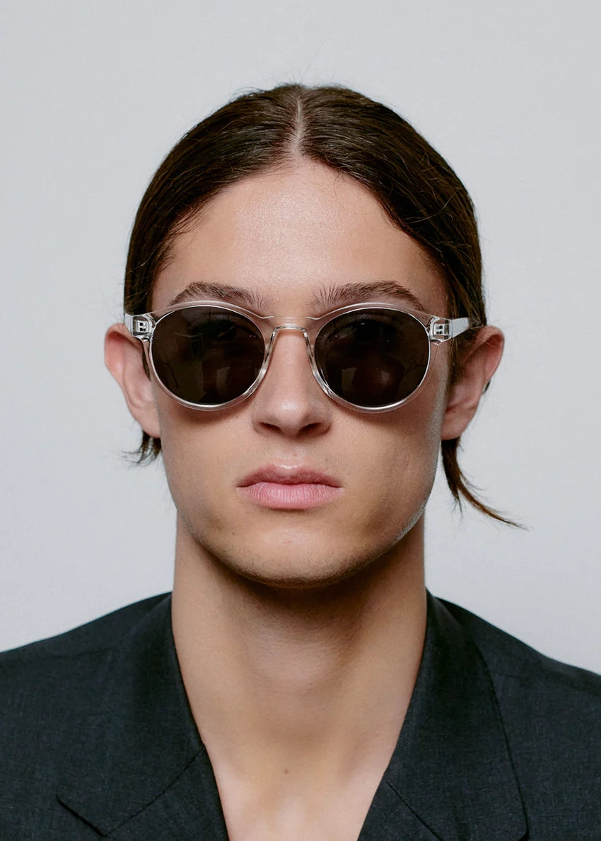 Person wearing round sunglasses with a neutral background