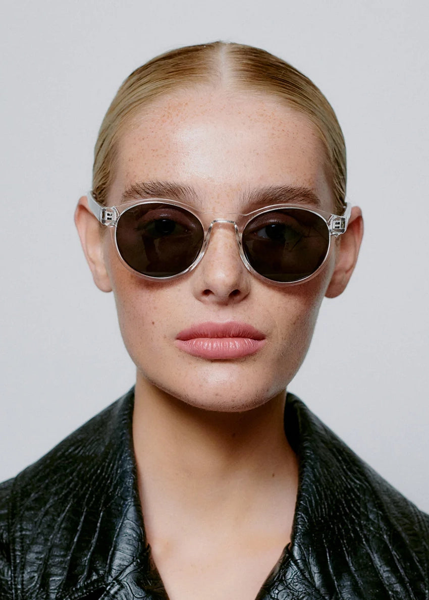 Woman wearing sunglasses and a black leather jacket against a plain background