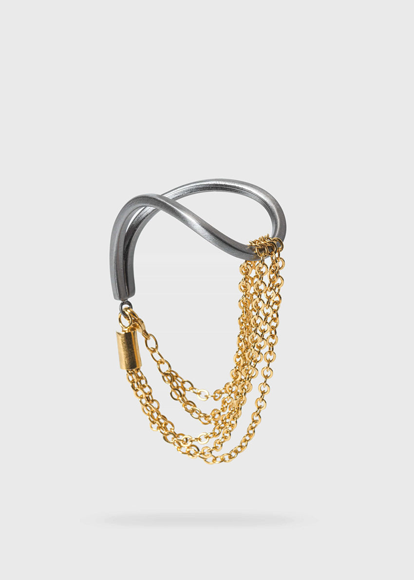 The epitome of modern elegance. A thin, metallic rod with inspired curves coexists with a delicate chain in a piece of jewellery that impresses with its ingenious design. Modern finesse in a bracelet that adds glow and sophistication to the look. 