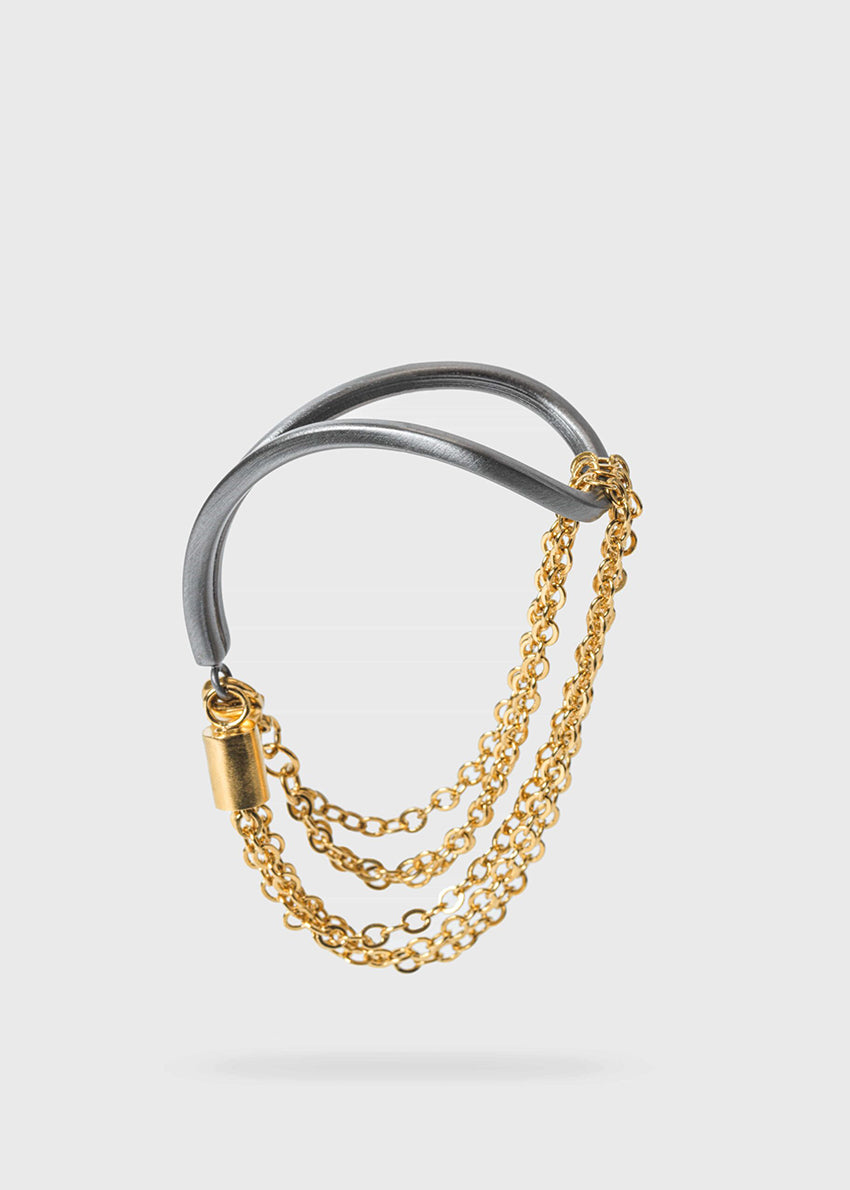 A gold and gun metal plated bracelet with a thin metallic rod and a delicate chain.