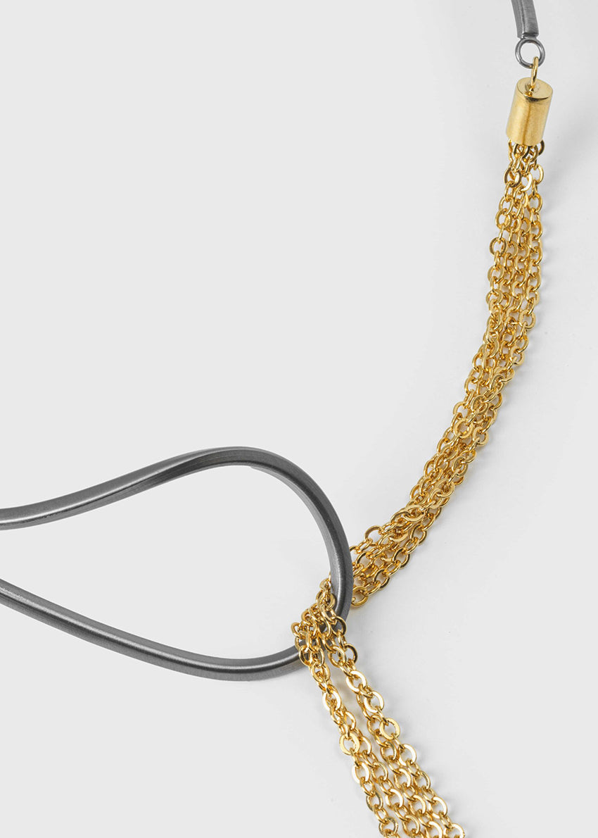 The epitome of modern elegance. A thin, metallic rod with inspired curves coexists with a delicate chain in a piece of jewellery that impresses with its ingenious design. Modern finesse in a necklace that adds glow and sophistication to the look. 