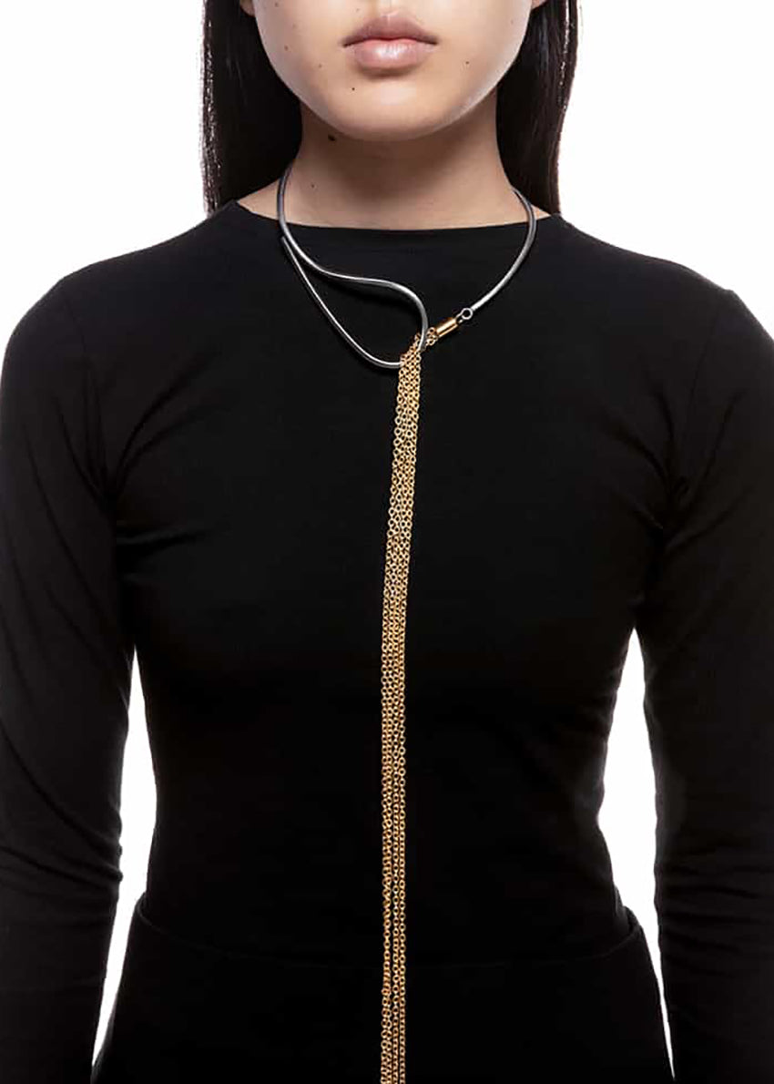 The epitome of modern elegance. A thin, metallic rod with inspired curves coexists with a delicate chain in a piece of jewellery that impresses with its ingenious design. Modern finesse in a necklace that adds glow and sophistication to the look. 