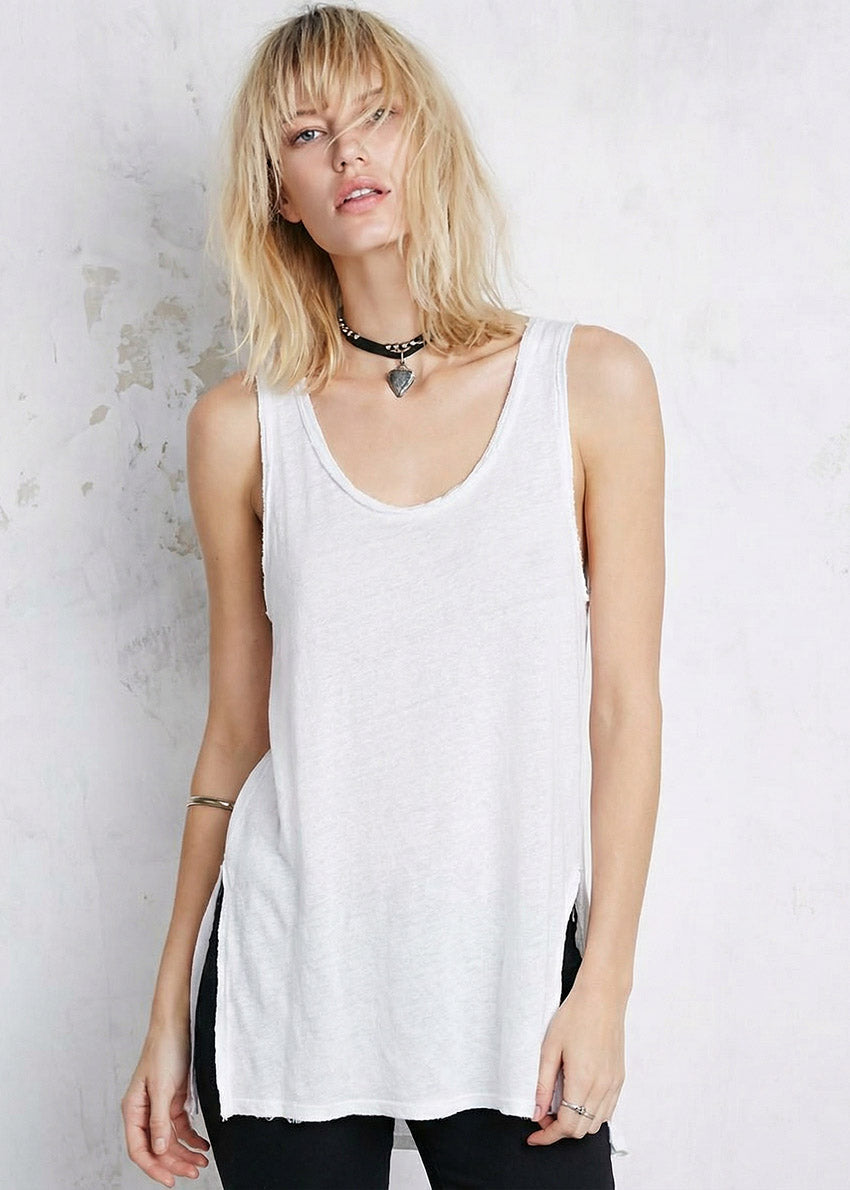 Woman wearing a white sleeveless top against a light background