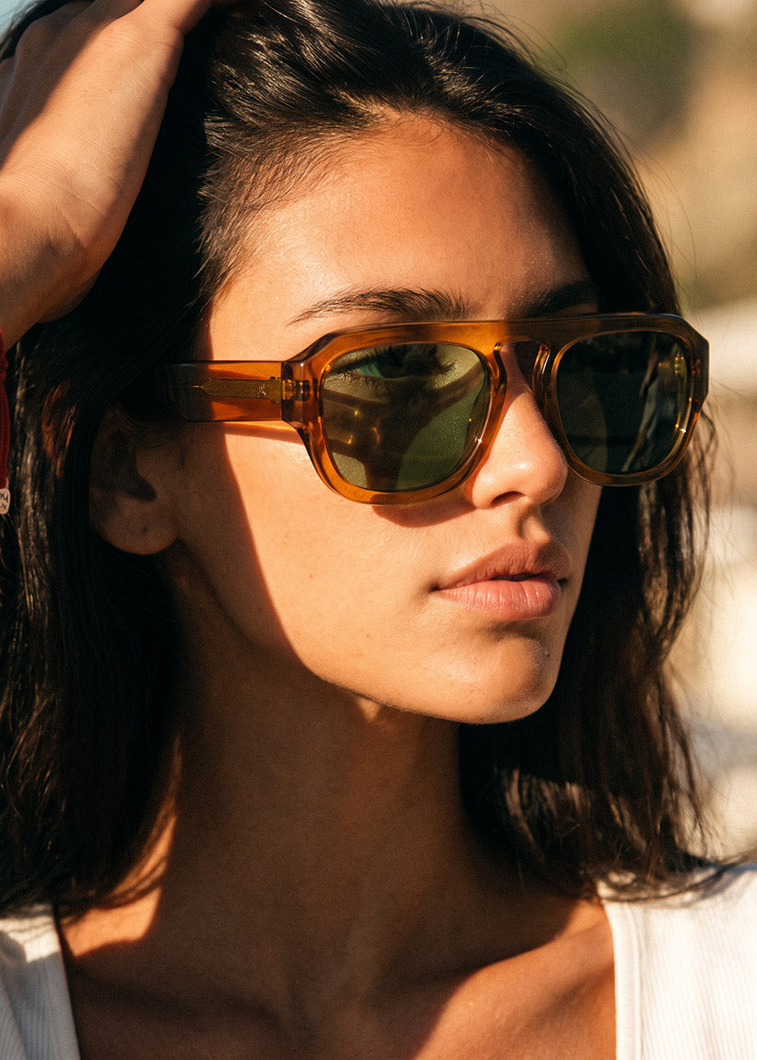 Sunglasses with brown frame and green lenses on a white background