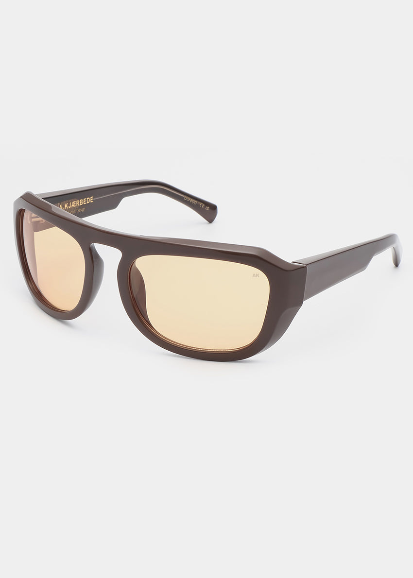 Sunglasses with brown frame and yellow-tinted lenses on a white background
