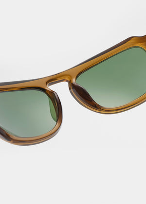 Sunglasses with brown frame and green gradient lenses on a light gray background
