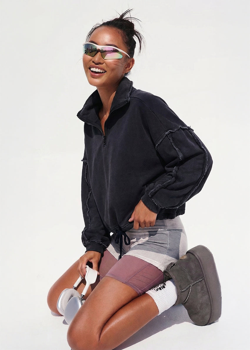 Person wearing a black jacket, gray shorts, and gray shoes on a white background