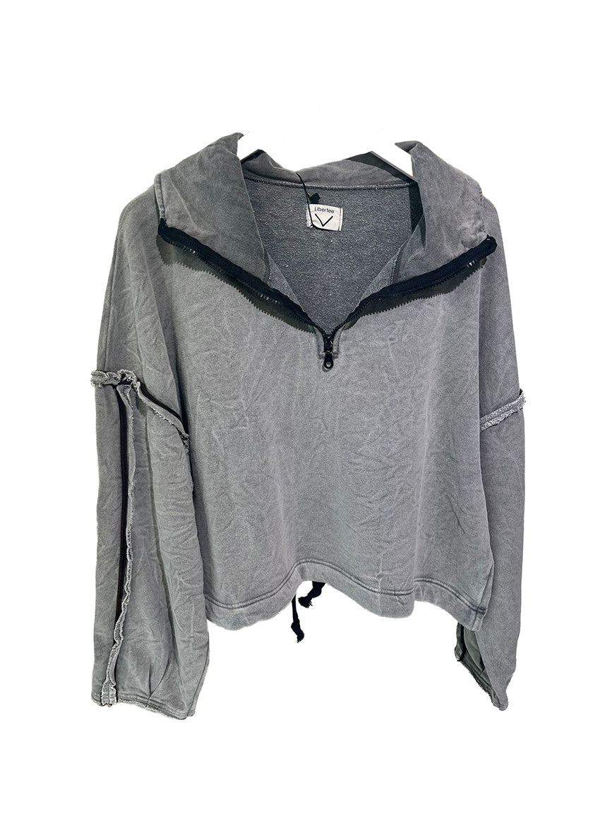 Woman wearing a gray sweatshirt and purple shorts sitting on a white background