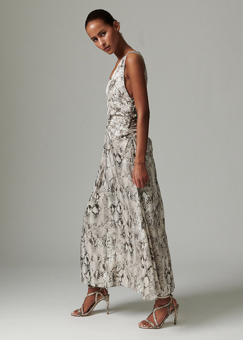 Woman wearing a long, patterned dress against a plain background