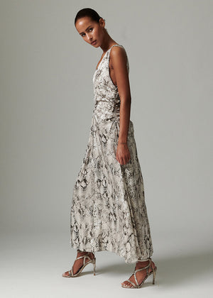 Woman wearing a long, patterned dress against a plain background