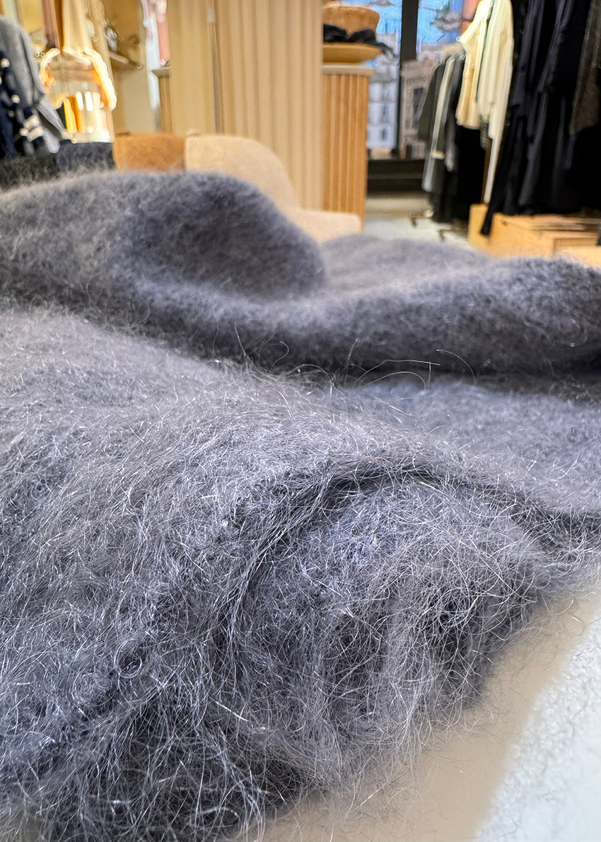 Close-up of gray mohair fabric with a clothing store in the background