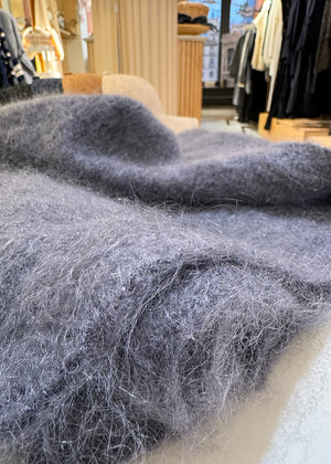 Close-up of gray mohair fabric with a clothing store in the background