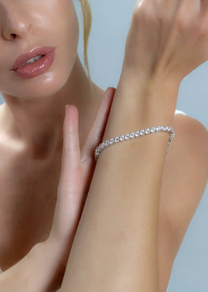 A tennis bracelet style arrangement featuring moissanite stones set in rhodium-plated sterling silver.