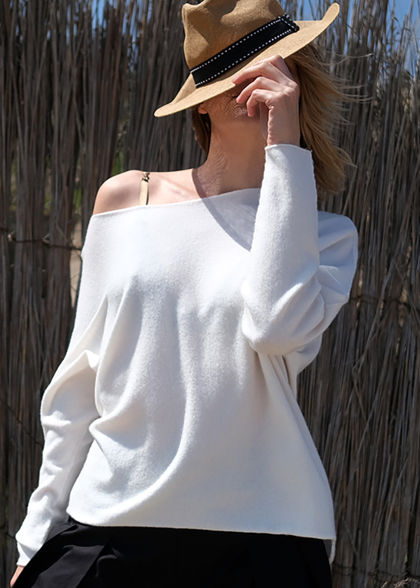 Woman hiding her face with a hat wear a white sweater