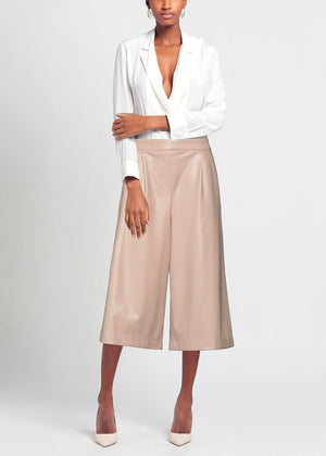 Woman wearing a white blouse and beige wide-leg pants on a light gray background