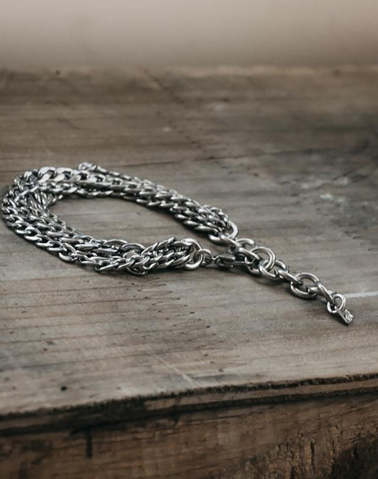A silver chunky chain bracelet displayed on a wooden surface.