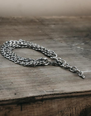 A silver chunky chain bracelet displayed on a wooden surface.