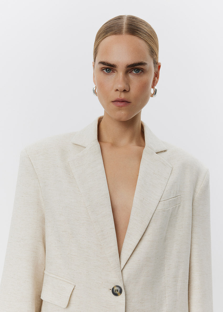 Woman wearing a light-colored blazer against a plain background