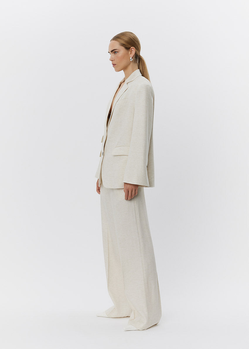 Woman wearing a beige suit standing against a white background