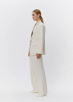 Woman wearing a beige suit standing against a white background