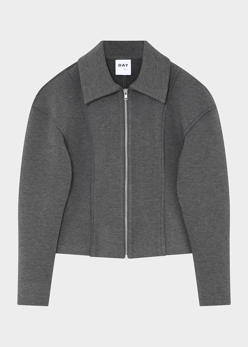 Woman wearing a gray zip-up jacket and skirt against a plain background