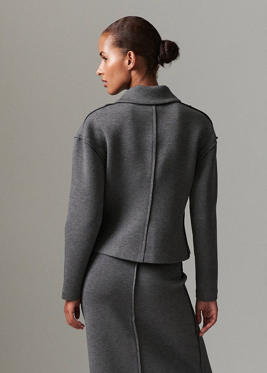 Woman wearing a gray suit against a plain background