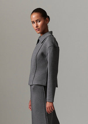 Woman wearing a gray suit against a plain background