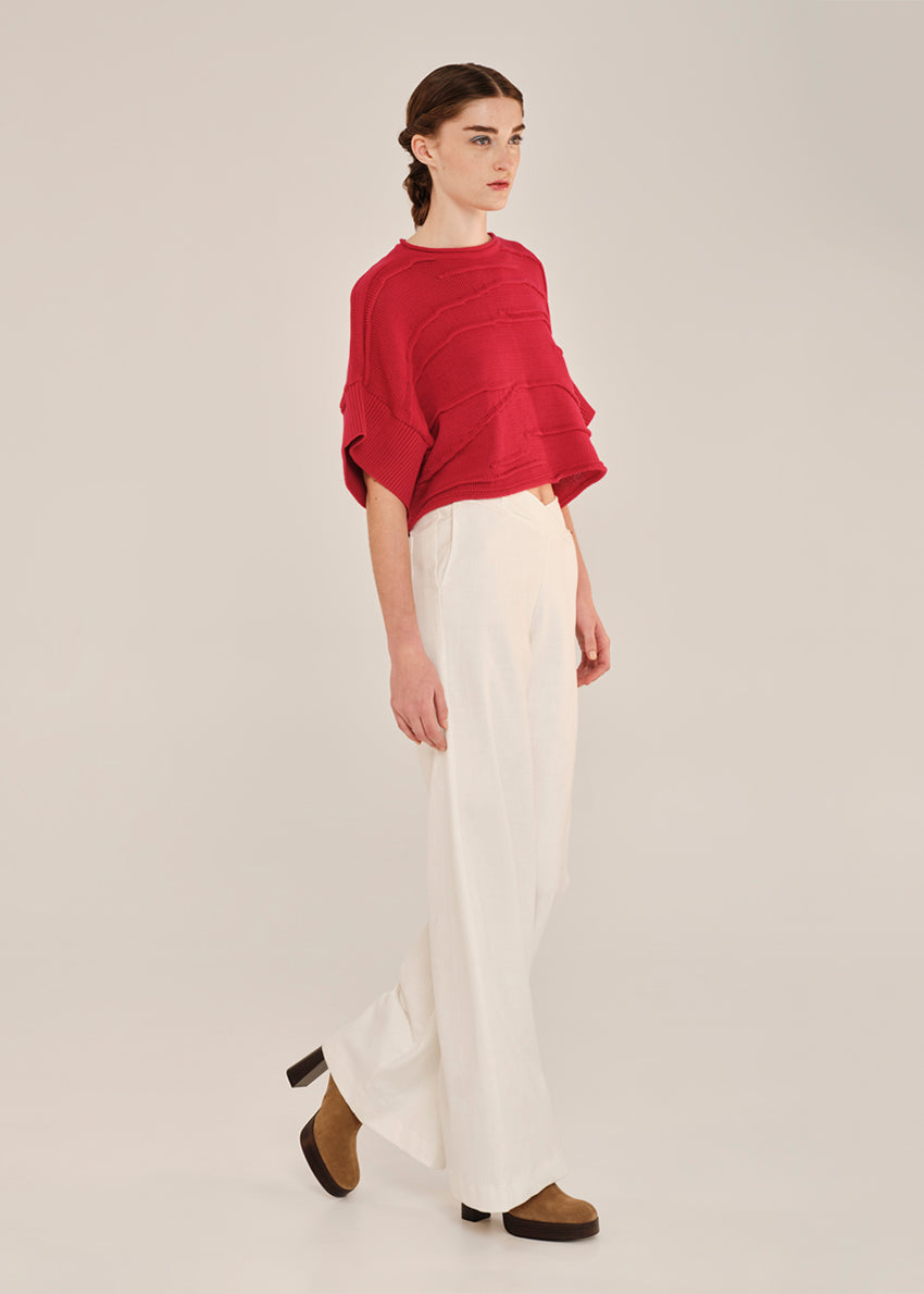 Person wearing a red top and white pants on a plain background