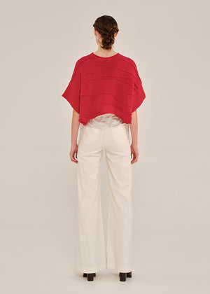 Person wearing a red top and white pants on a plain background