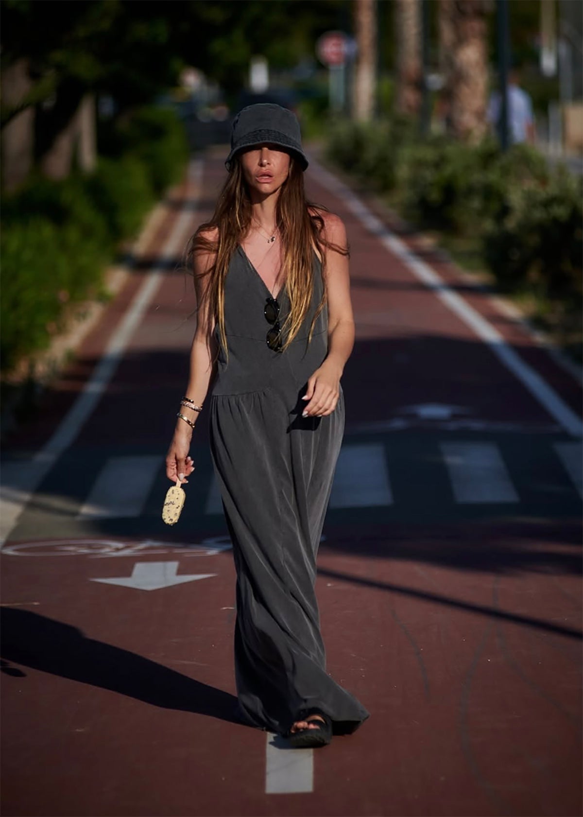 Woman wearing a dark dress with a backless design, holding a plant, on a blurred background.