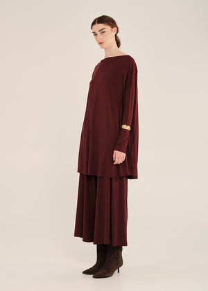 Woman wearing a burgundy oversized top with long sleeves on a white background