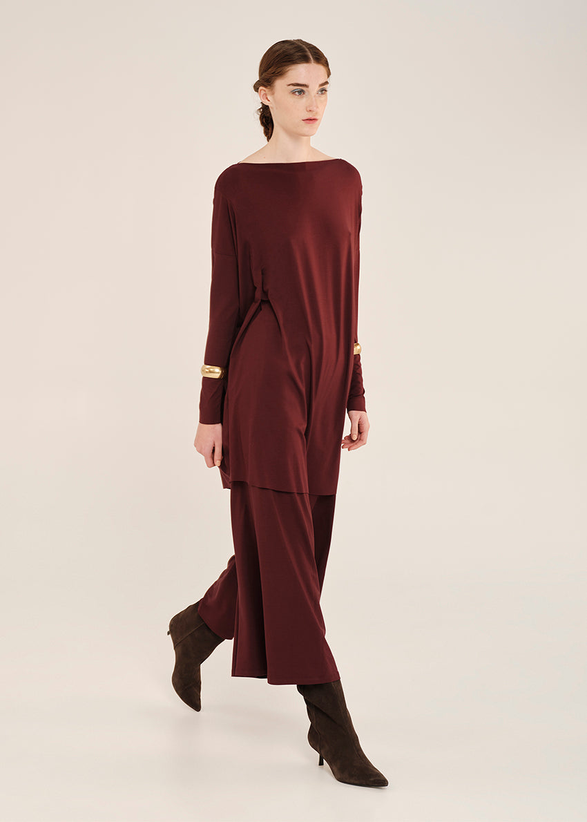 Woman wearing a burgundy oversized tlop with long sleeves on a white background