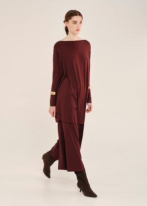 Woman wearing a burgundy oversized tlop with long sleeves on a white background