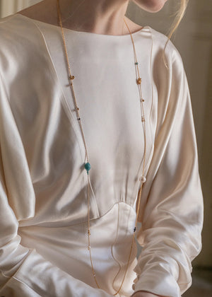 Person wearing a long beaded necklace with a blurred background