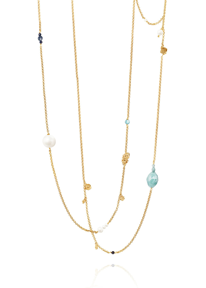 Layered gold necklace with various beads on a white background