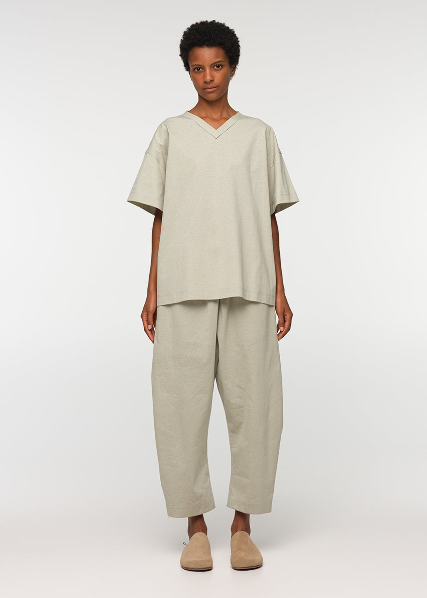 Unisex, mid-length beige trousers, made from soft, non-stretch rayon fabric, in a relaxed, organic cut, featuring a wide elastic waistband, a dropped crotch, and front pockets