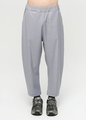 Unisex, mid-length grey trousers, made from soft, non-stretch rayon fabric, in a relaxed, organic cut, featuring a wide elastic waistband, a dropped crotch, and front pockets