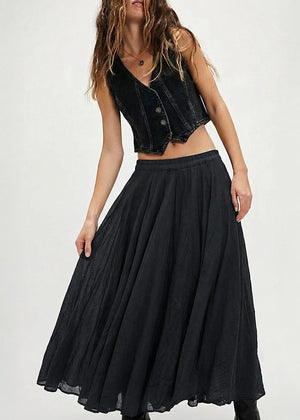 Woman wearing a black denim vest over a black skirt on a white background