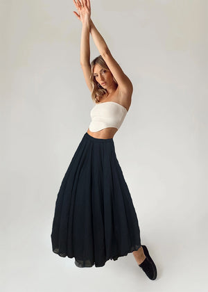 Woman wearing a white strapless top and black skirt against a plain background