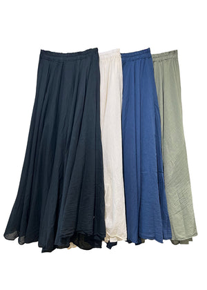 Four long skirts in black, white, blue, and green on a white background