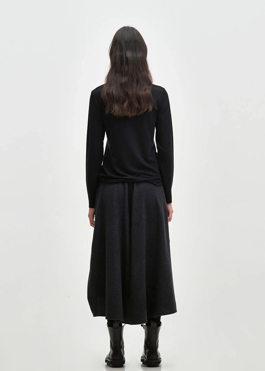 Asymmetrical skirt with a decorative diagonal ruffle made of soft blended wool flannel. ONDA features an elastic waistband and a zipper closure on the back side.