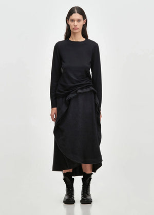 Asymmetrical skirt with a decorative diagonal ruffle made of soft blended wool flannel. ONDA features an elastic waistband and a zipper closure on the back side.