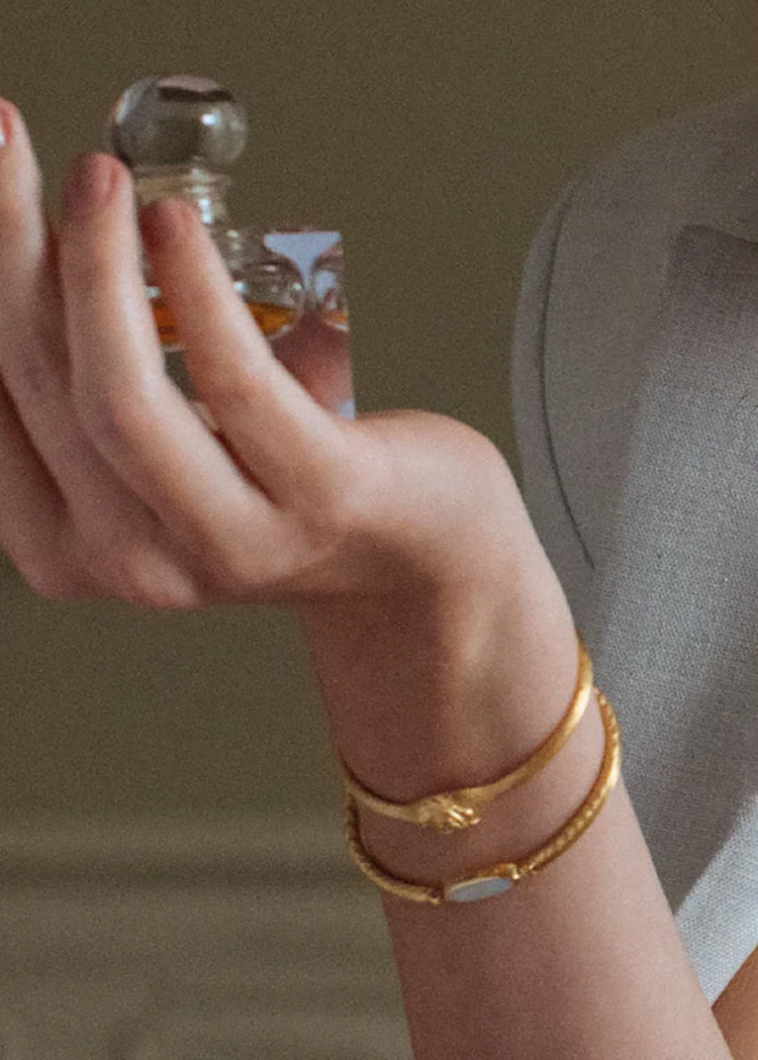 Hand holding a small glass bottle with a blurred background