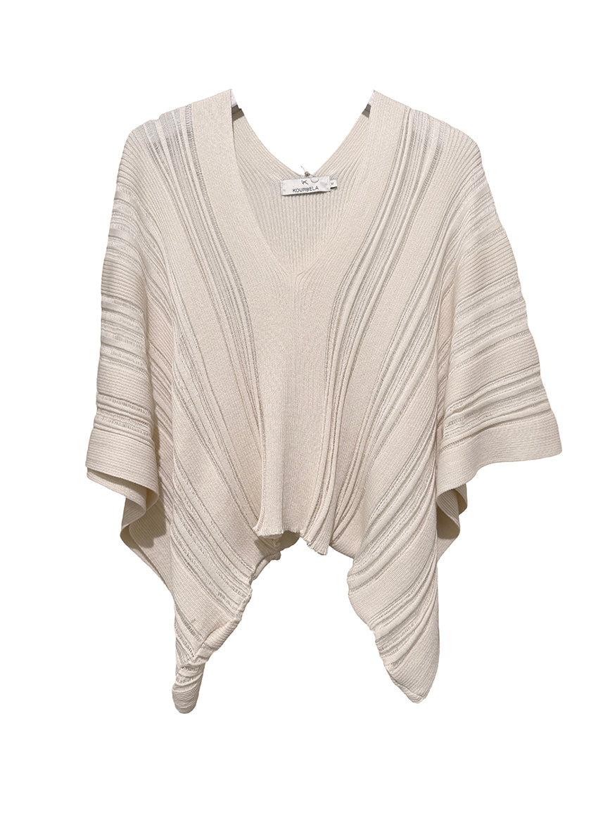 Close-up of a person wearing a beige ribbed sweater with a blurred background