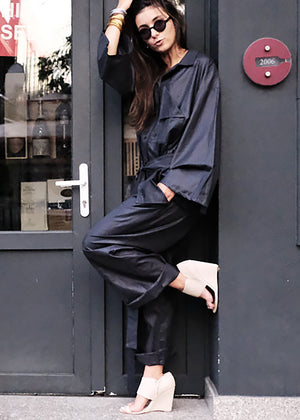 Woman in a black outfit standing against a gray door