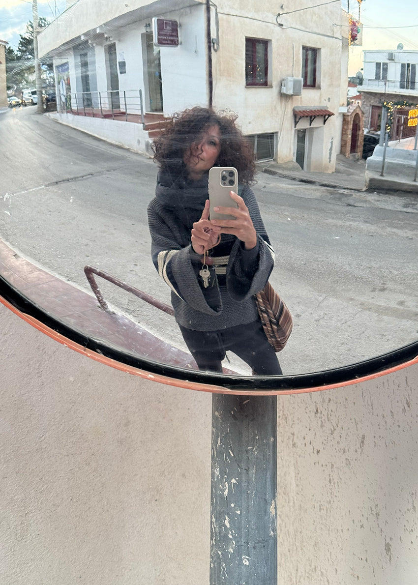 A long-sleeved Palma Sweater with a classic round neck, stripes, and bell sleeves in a mix of gray, navy, and beige colors.