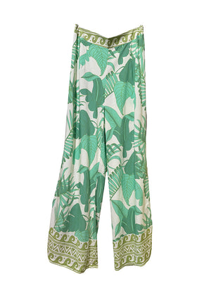A pair of flared rayon pants with a green leaf pattern and decorative trim at the waist.